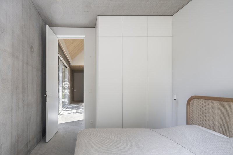 Bedroom with exposed concrete walls and ceiling featuring a full-height white storage cabinet