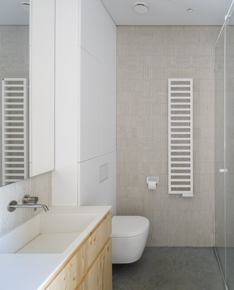 Bathroom interior with pale wood vanity, white towel radiators, and vertical tile accent wall