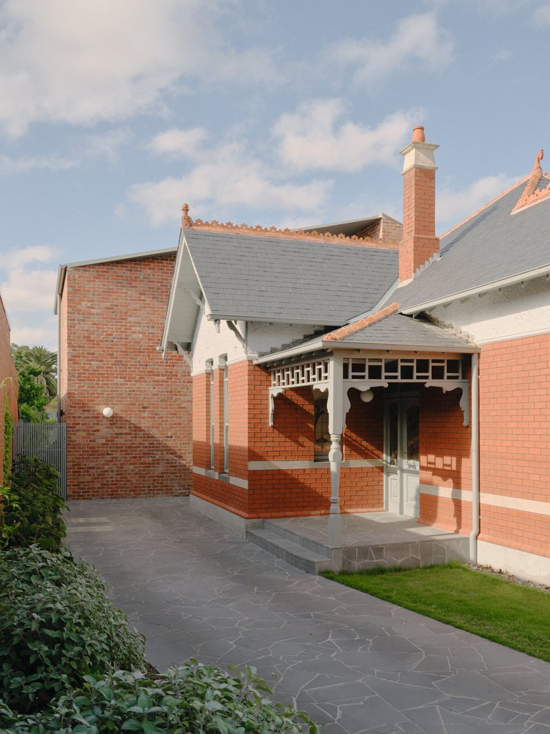 Rear courtyard showing red brick porch with decorative timber brackets and dark stone paving