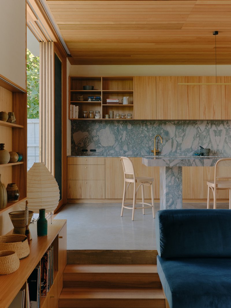 Kitchen with vertical timber cabinetry, blue marble island and natural light through clerestory windows