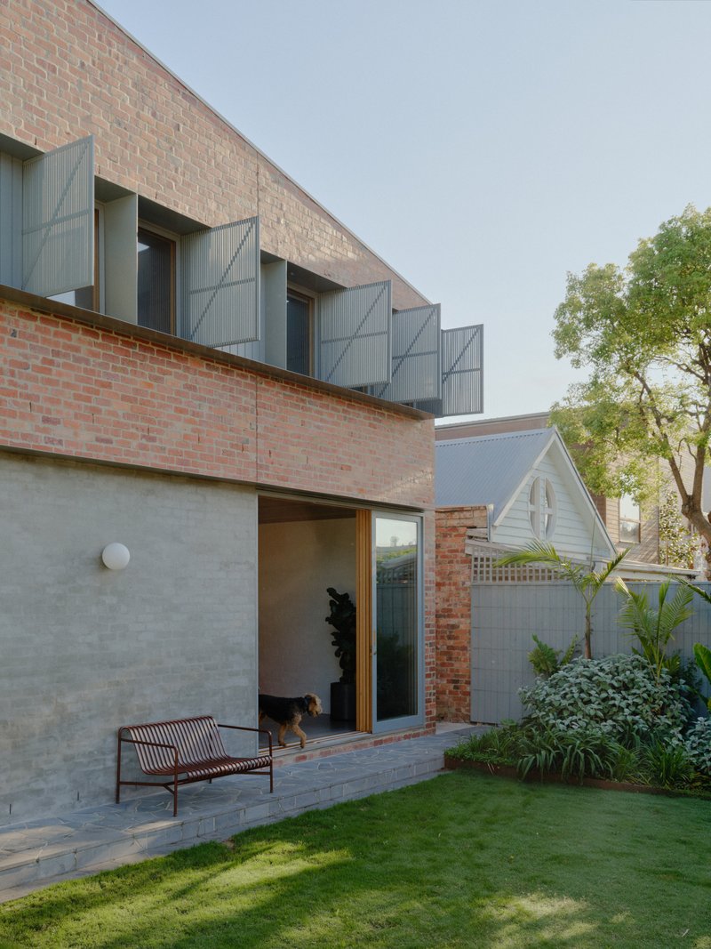 Courtyard elevation showing brick upper level with metal shutters and dog in doorway