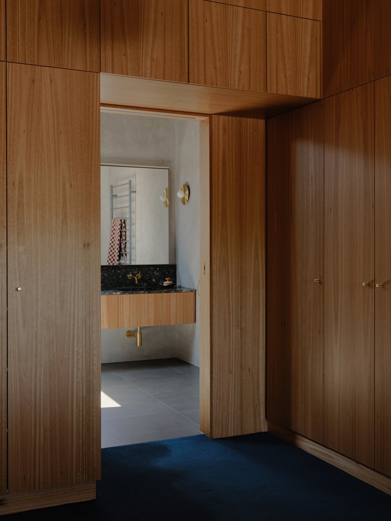 Timber-lined dressing room with blue carpet looking through doorway to bathroom beyond