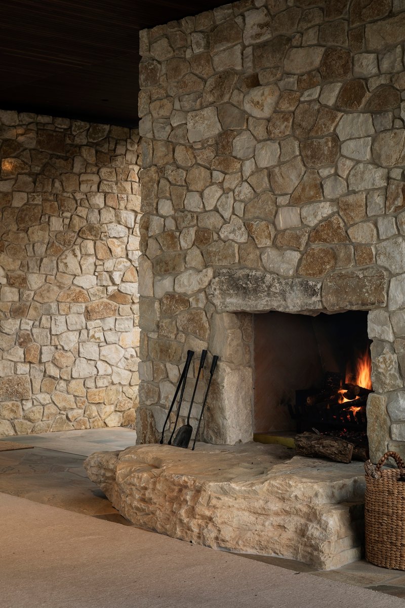 Irregular stone fireplace with active fire and raised stone hearth platform in low light