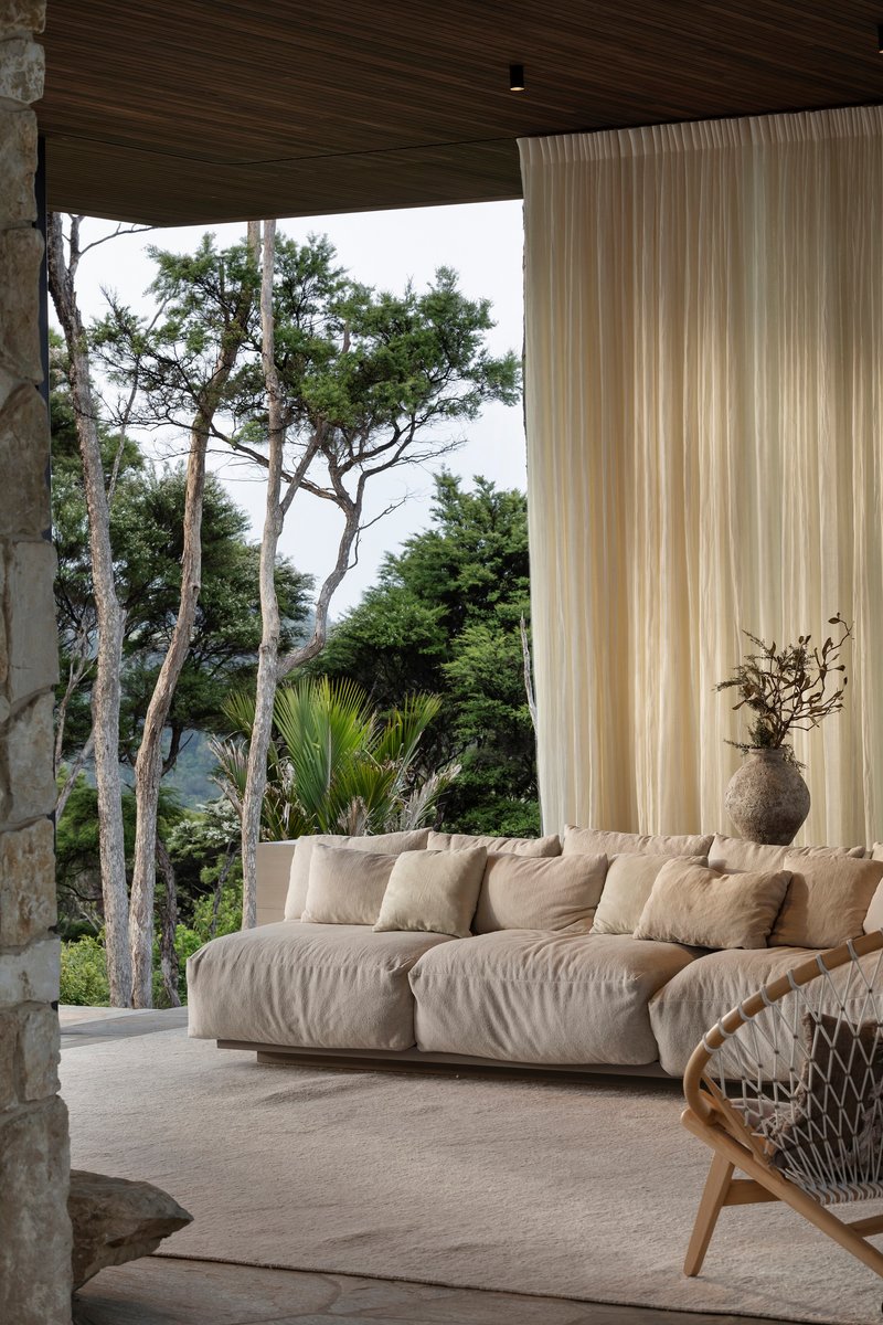 Covered terrace with timber ceiling opening to native trees and coastal vegetation beyond