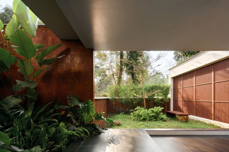 View from interior terrace across planted beds toward timber-screened facade and garden courtyard