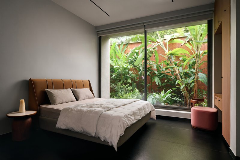 Bedroom with full-height glass doors opening to a planted garden bed with banana leaves