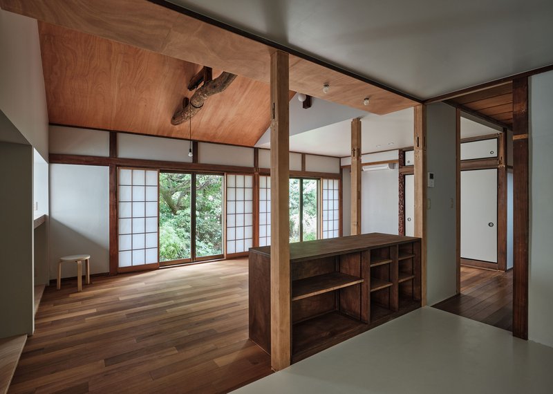 Interior room with translucent sliding screens opening to greenery and a low timber storage unit