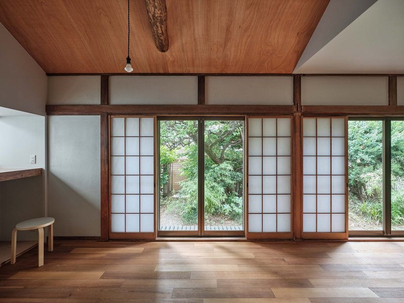 Wall of translucent sliding screens with timber frames overlooking a garden with trees and foliage