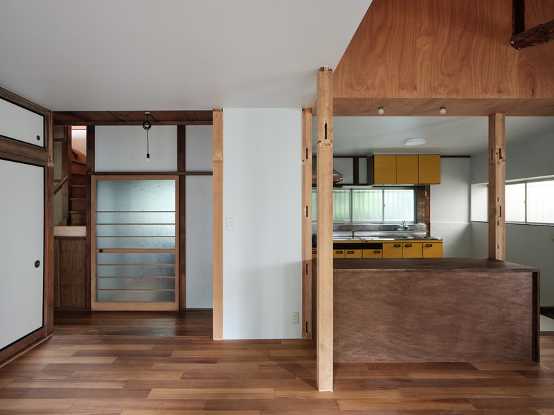 Timber framed passage with sliding translucent panels opening toward the kitchen area beyond