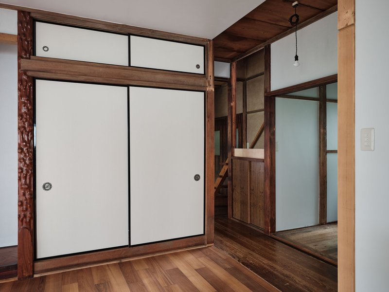 White paper sliding doors and exposed timber columns framing a staircase in the background