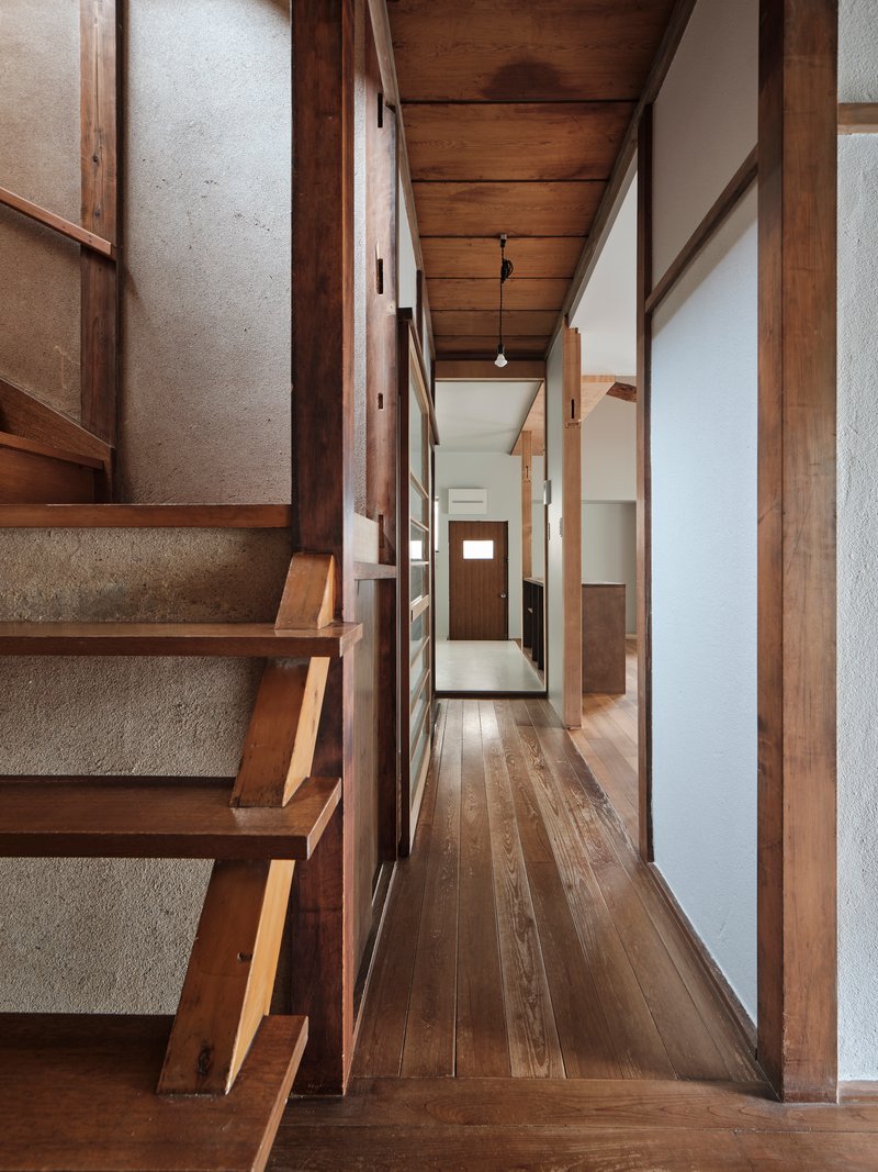 Timber staircase with open risers adjacent to a narrow hallway with paper screen walls