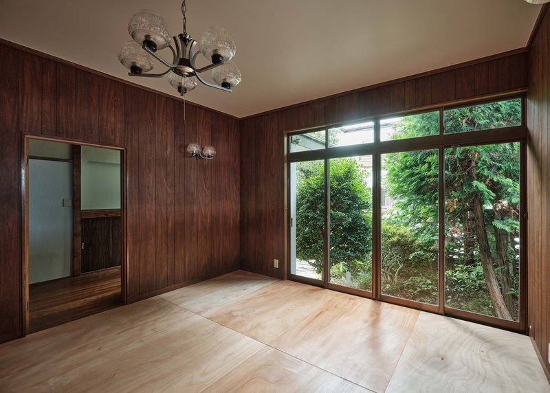 Wood-paneled room with floor-to-ceiling windows framing dense greenery outside