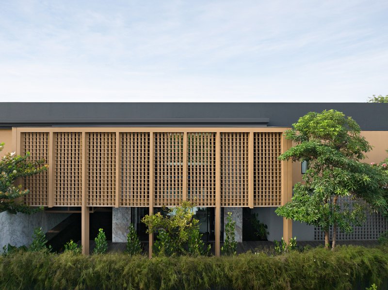 Timber lattice screen facade elevated on columns with grasses and trees in the foreground