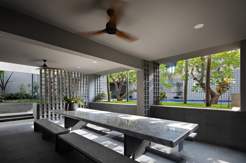 Open-air dining pavilion with stone table and breeze block screens overlooking the garden courtyard
