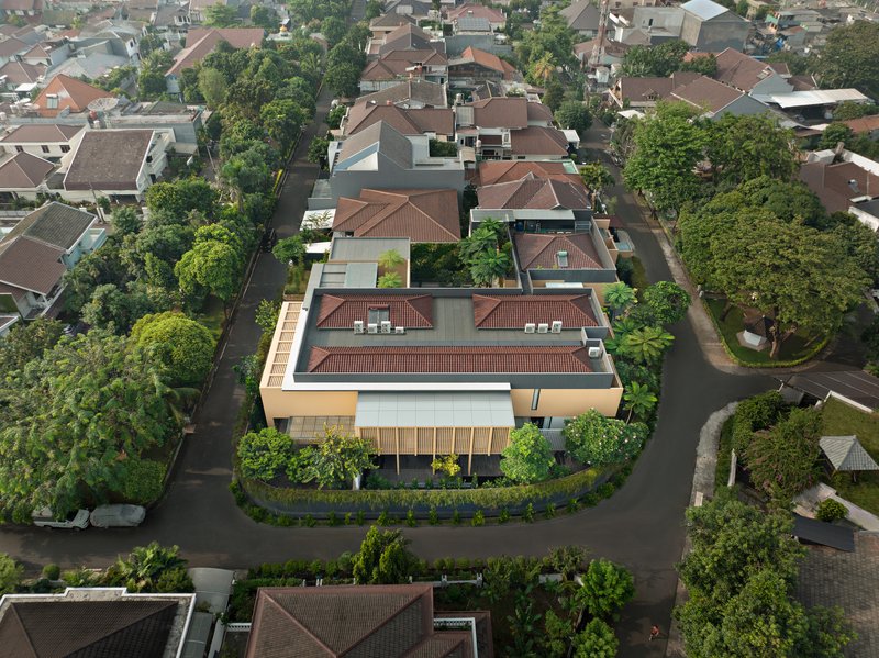 Aerial view of the residence with terracotta tile roof and cream facade surrounded by neighboring houses and trees