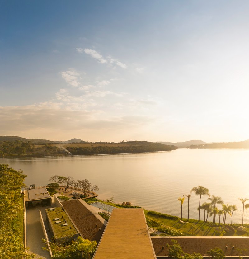 Aerial view of the lakeside terrace and sloped roof planes at sunset with palm trees below