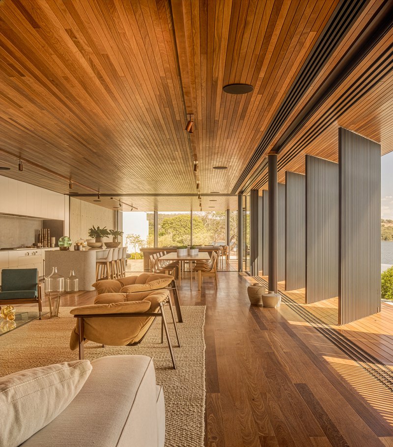 Open-plan living space with timber slat ceiling and sliding screens casting afternoon shadows on the floor