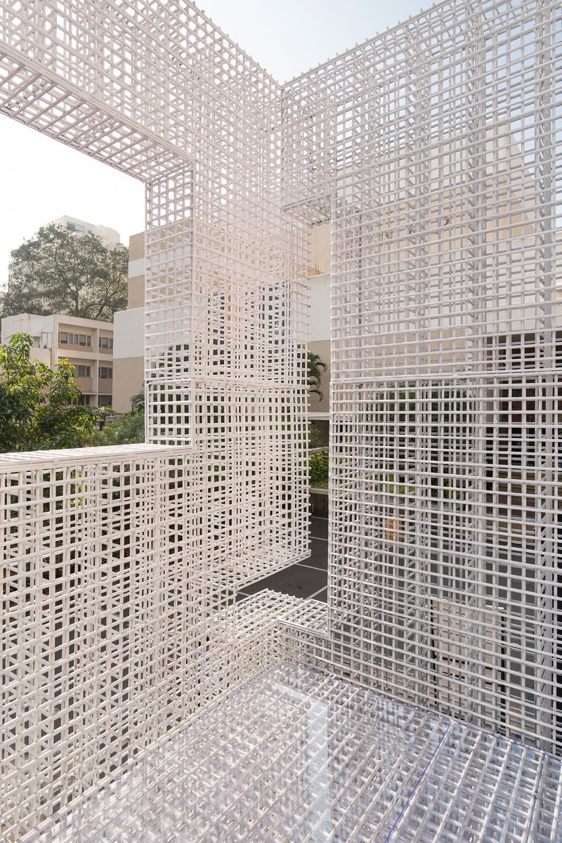 Corner courtyard enclosed by white lattice mesh walls and ceiling open to sky