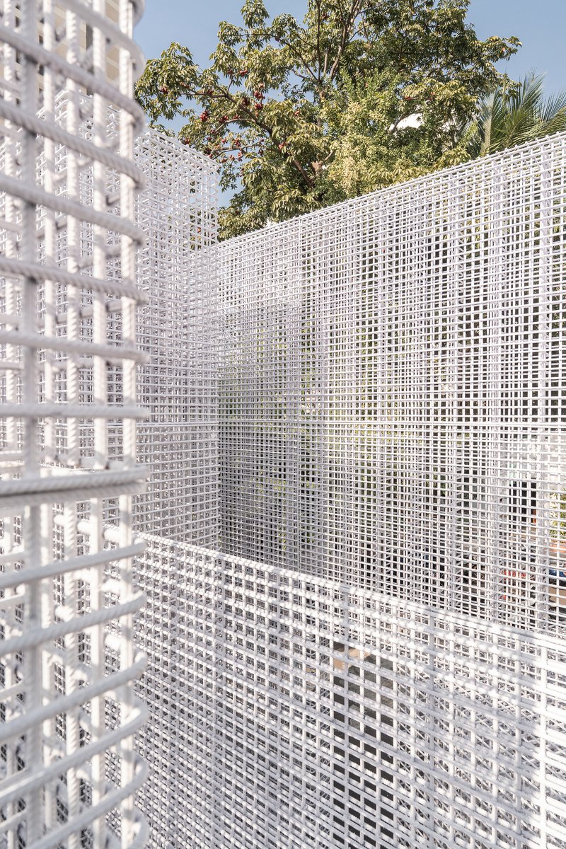 Close-up of white gridded mesh screen showing corner intersection with trees visible beyond