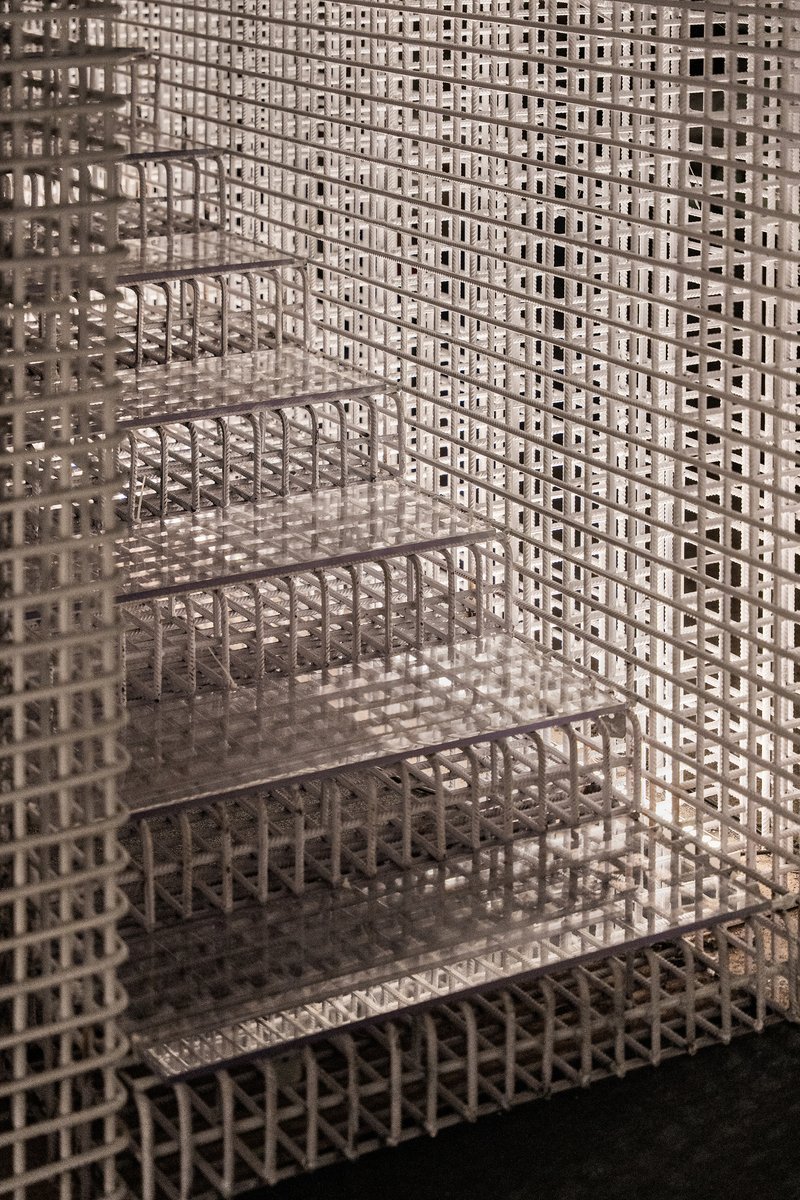 Glass shelving embedded within white lattice screen walls casting patterned shadows
