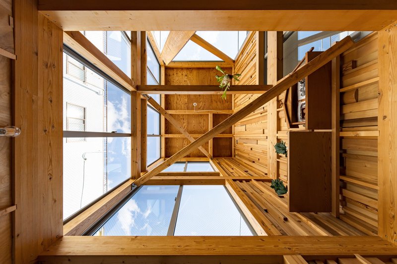 Upward view through the central void showing timber framing and glass floor panels