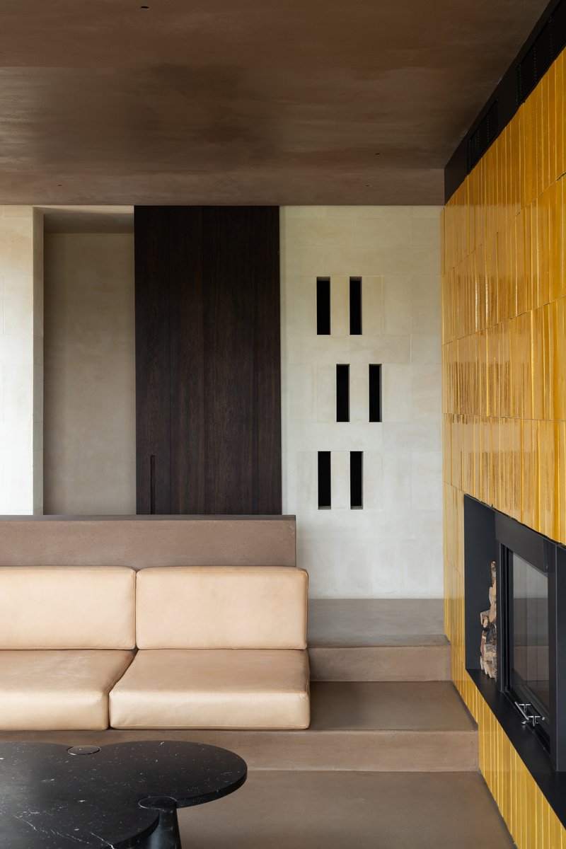 Interior view showing timber fireplace surround and built-in seating beside vertical slot openings in wall