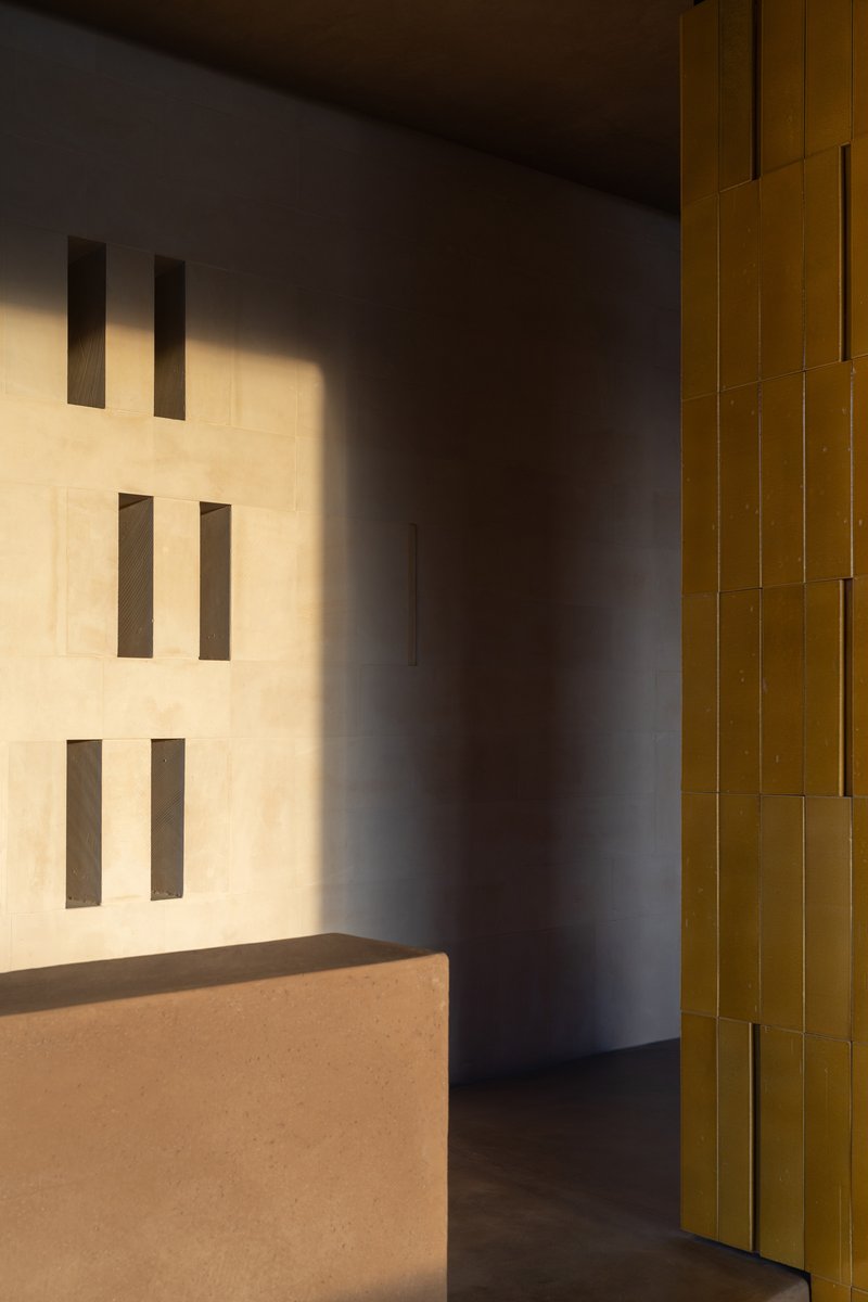 Corner detail showing rectangular wall openings and yellow glazed tile column in afternoon light