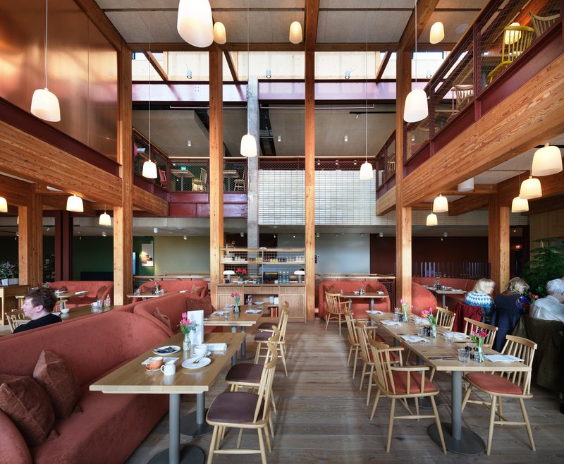 Dining area with timber frame structure, pendant lights, and red upholstered banquette seating