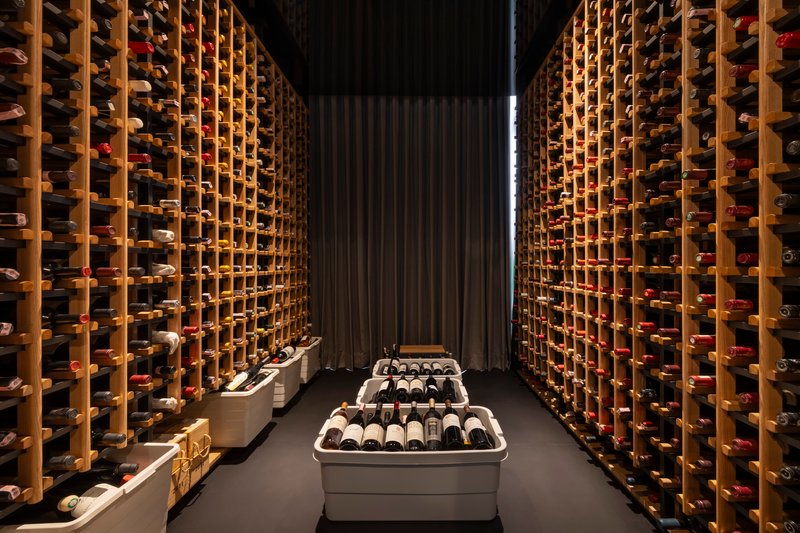 Wine cellar with floor-to-ceiling timber racking illuminated by vertical strip lighting