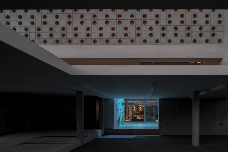 Parking garage interior at dusk with perforated ceiling soffit and illuminated entrance beyond