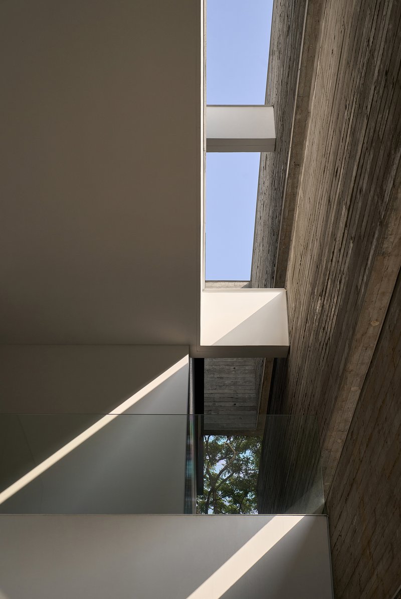 Interior stairwell skylight framed by board-formed concrete beams and white plaster walls