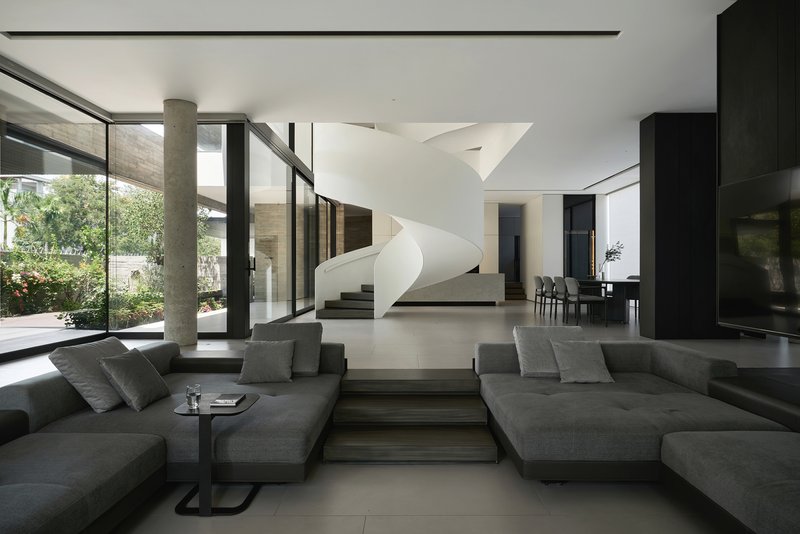 Double-height living room with a white helical staircase and floor-to-ceiling glass overlooking the garden