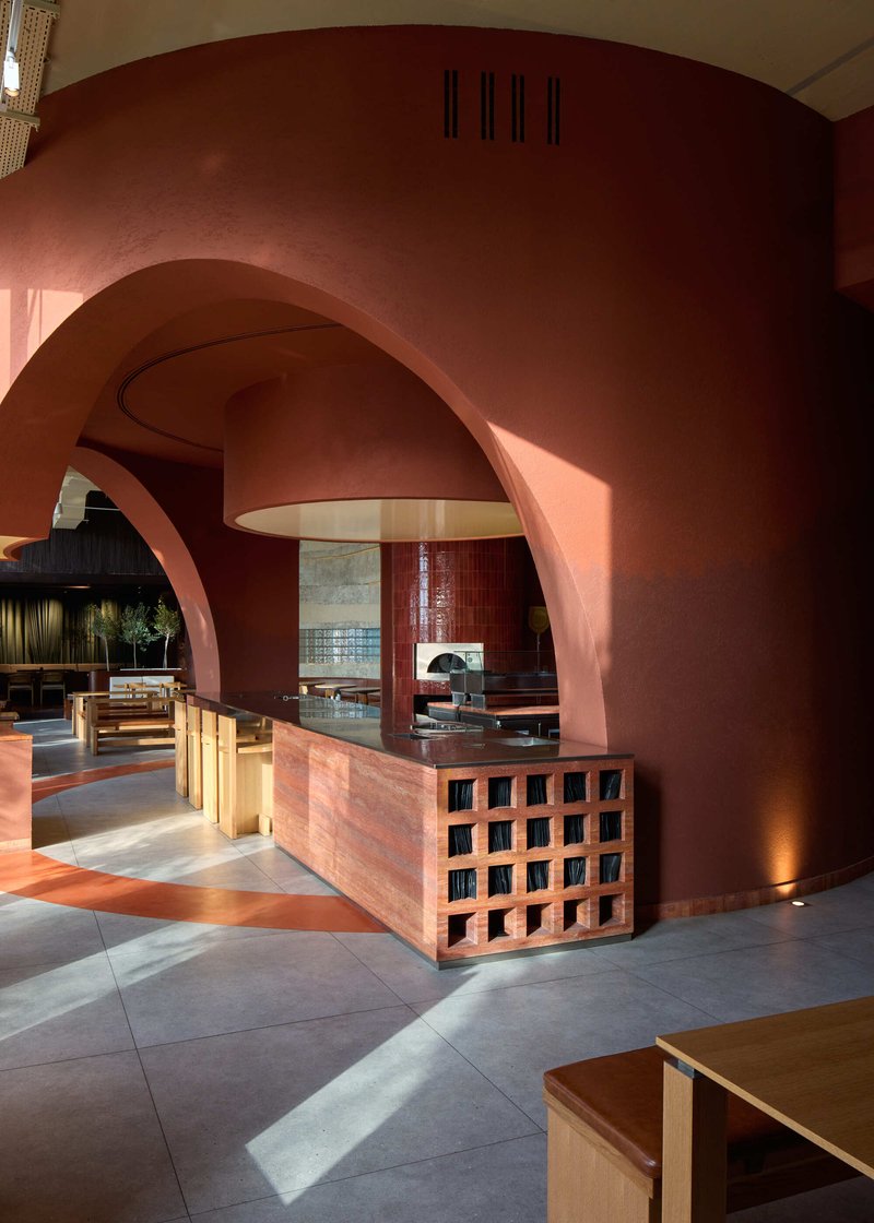 Reception counter with latticed base beneath layered terracotta arches and suspended pendant fixture