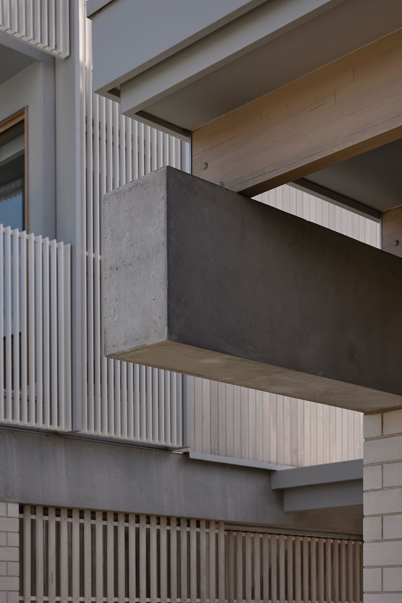 Close-up of cantilevered concrete balcony with timber soffit and vertical slatted screen above