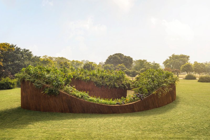 Side view of the undulating planted wall rising from cropped grass in soft afternoon light