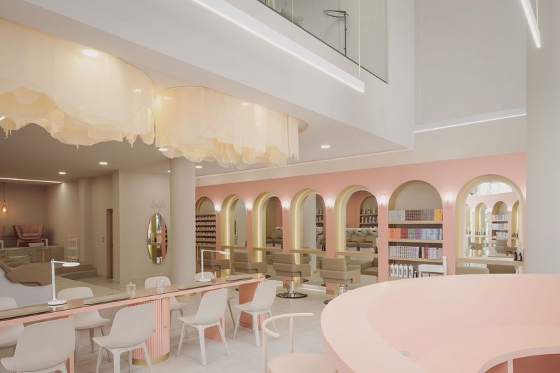 Double-height interior with a pink arcaded wall, white seating area and mural on the ceiling