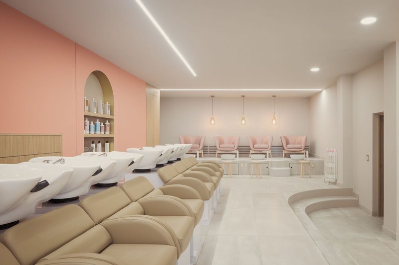 Salon interior with rows of hair-washing stations, pedicure chairs and pink millwork under linear lighting