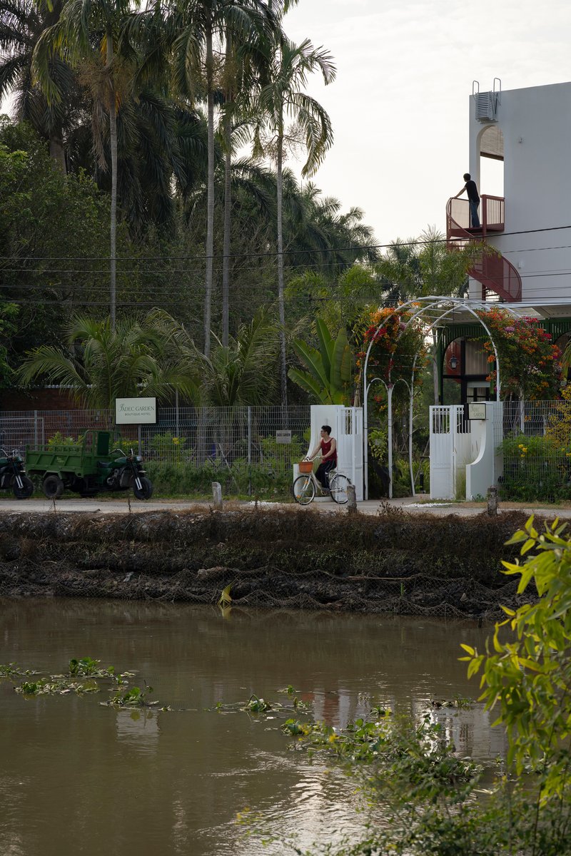 Street view across a canal showing the white arched entry gate with a cyclist passing by