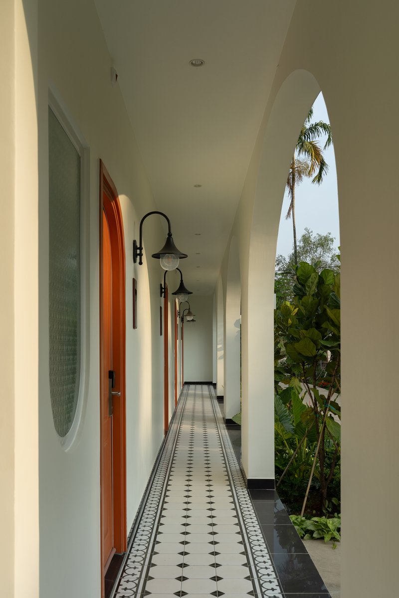 Covered corridor with patterned tile flooring and pointed arch opening revealing palm trees and banana plants