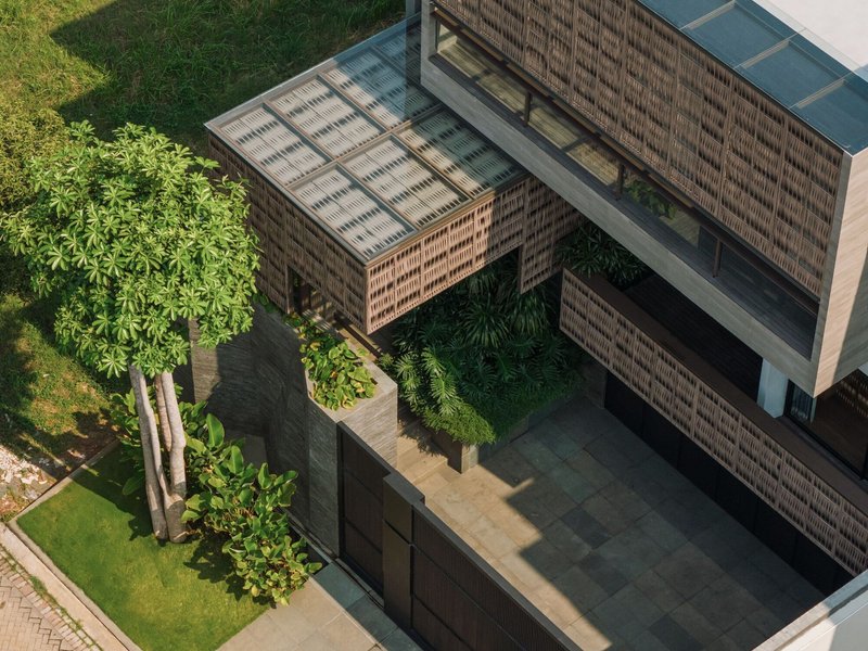 Aerial view of the brick-screened volumes framing a central courtyard with planted trees