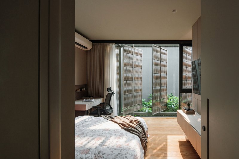 Bedroom view through open sliding doors to a courtyard with lattice screens and small planted garden