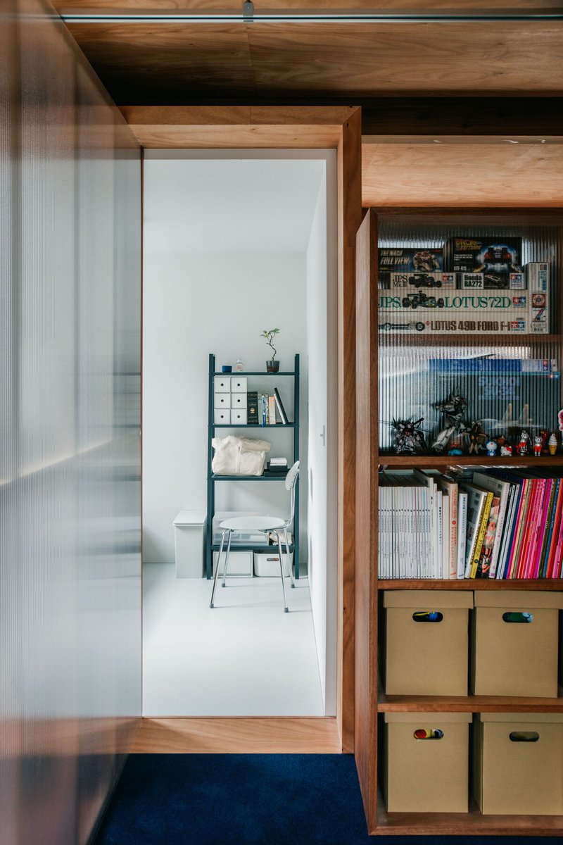 Timber-framed doorway opening to a white room with built-in shelving holding storage boxes