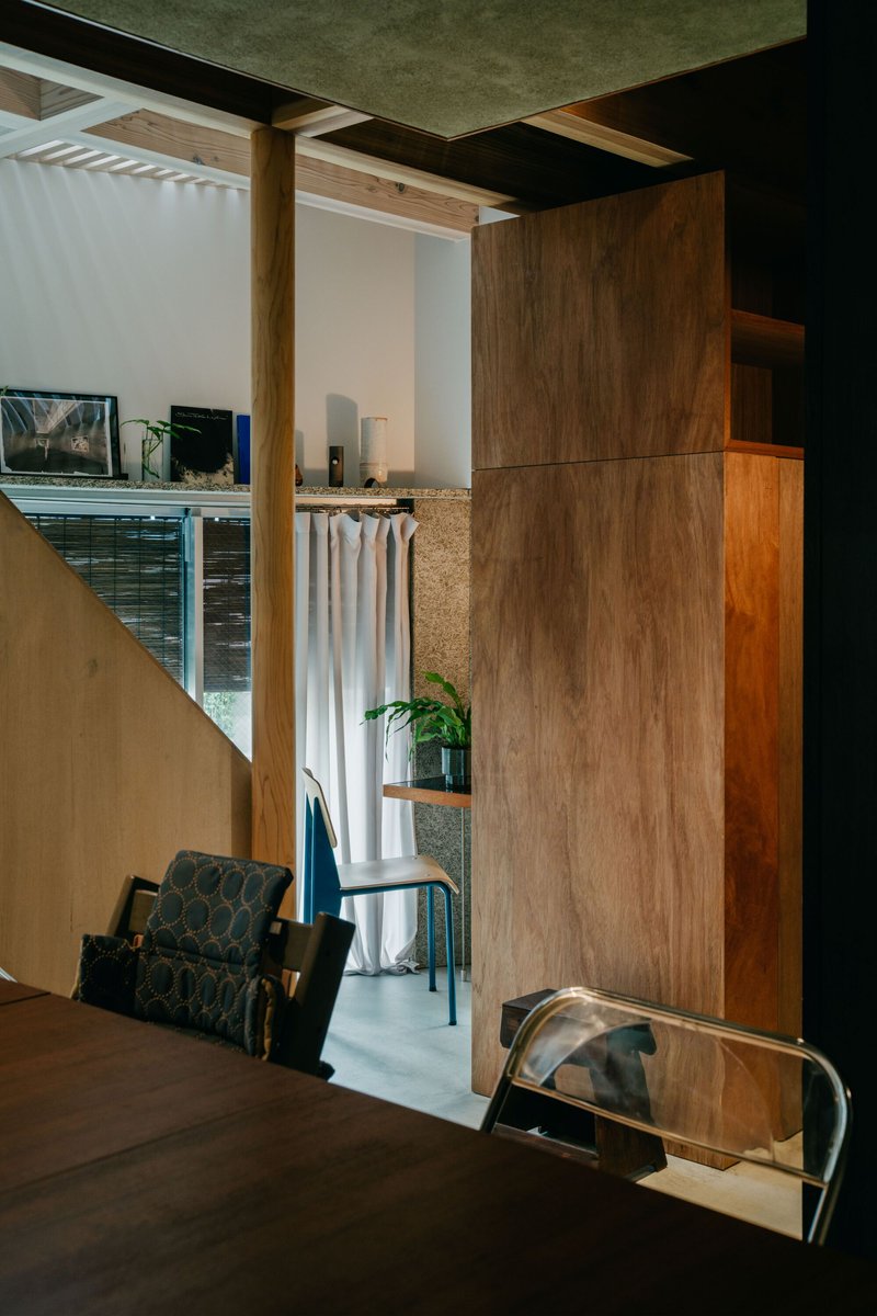 Split-level interior with walnut millwork and exposed timber columns framing curtained openings