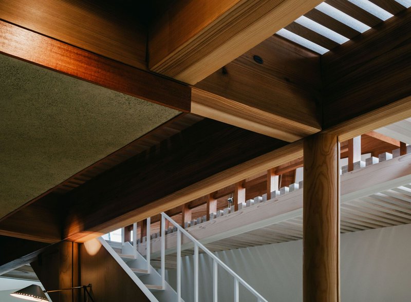 Interior view of exposed timber beams and white staircase with skylights above