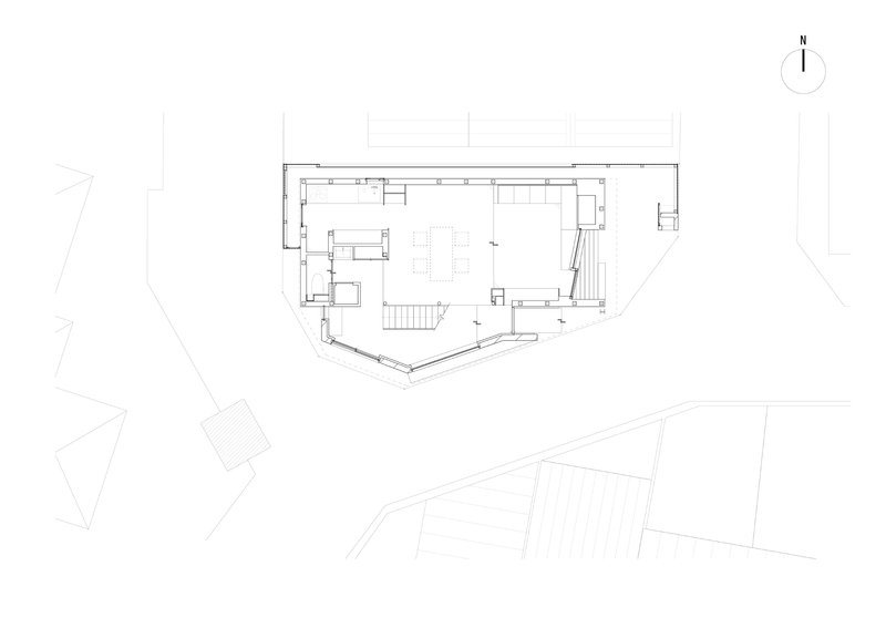 Floor plan drawing showing an angled rectangular volume with central staircase and surrounding site context