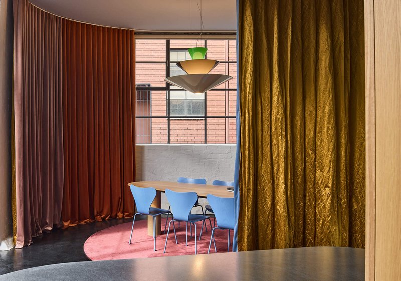 View through golden curtain towards seating area with layered textile partitions in varied hues