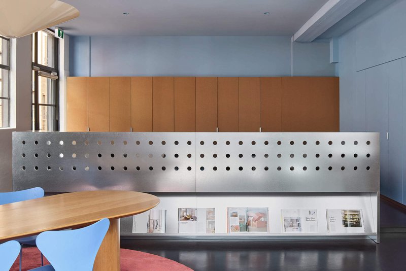 Perforated metal balustrade with timber cabinetry above and magazine display shelf below
