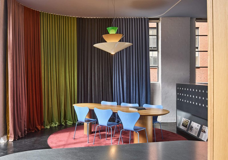 Workspace interior with gradient curtain wall transitioning from terracotta through green to charcoal