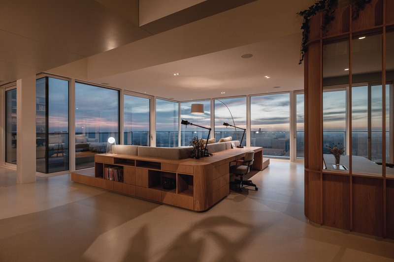 Open living space with floor-to-ceiling glazing overlooking the city at dusk