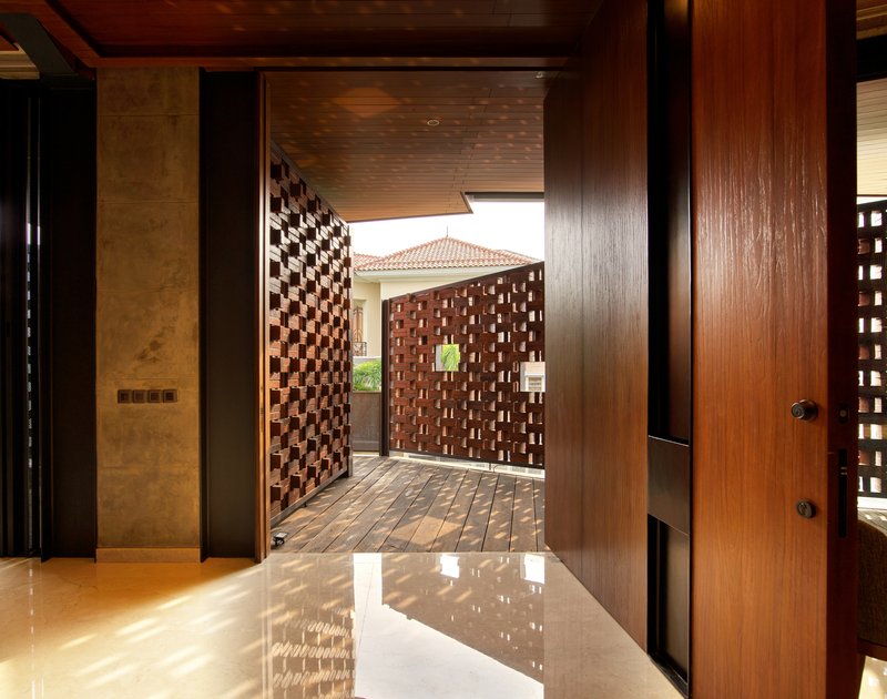 View through timber doorway to exterior courtyard framed by basketweave brick screens in daylight
